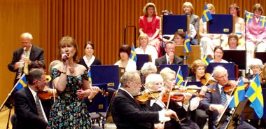 Eva Magnusson, sångsolist, omgiven av medlemmar i Arosorkestern vid konsert i Västerås Konserthus den 6 juni 2006.